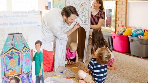 Adults playing with children in a playroom