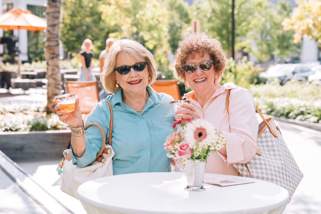 Two women laughing and toasting drinks at Avenue East Cobb Ladies Night.